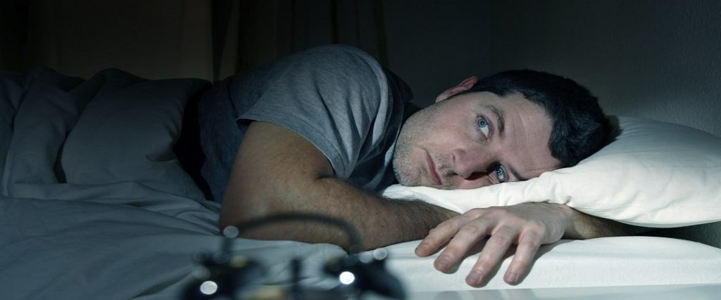 Sleepless man lying in bed.