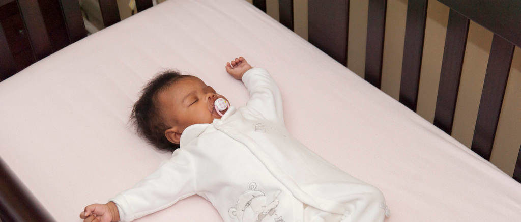 Baby lying on a mattress in a crib