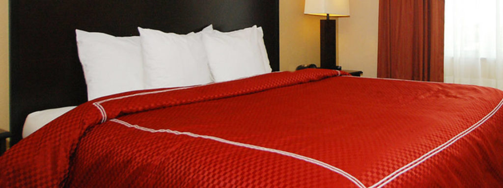 A king sized bed / mattress with a red sheet on